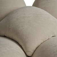 Soft beige decorative pillows featuring a smooth, textured fabric in a layered arrangement.