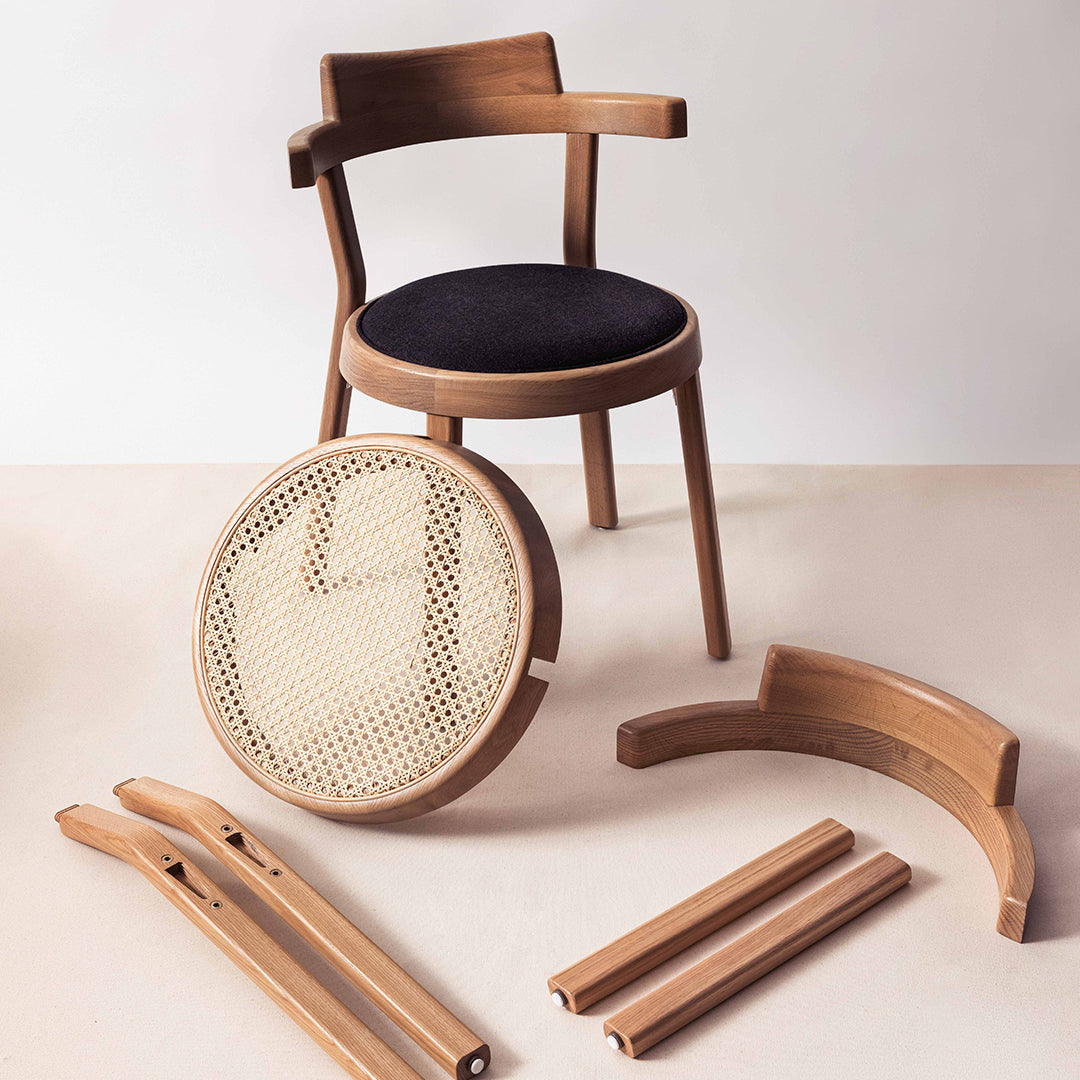 Natural wood chair with dark upholstered seat and woven cane back; featuring smooth, light wood accents and warm tones.