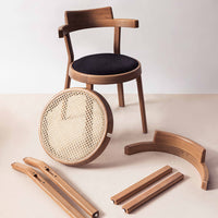 Natural wood chair with dark upholstered seat and woven cane back; featuring smooth, light wood accents and warm tones.