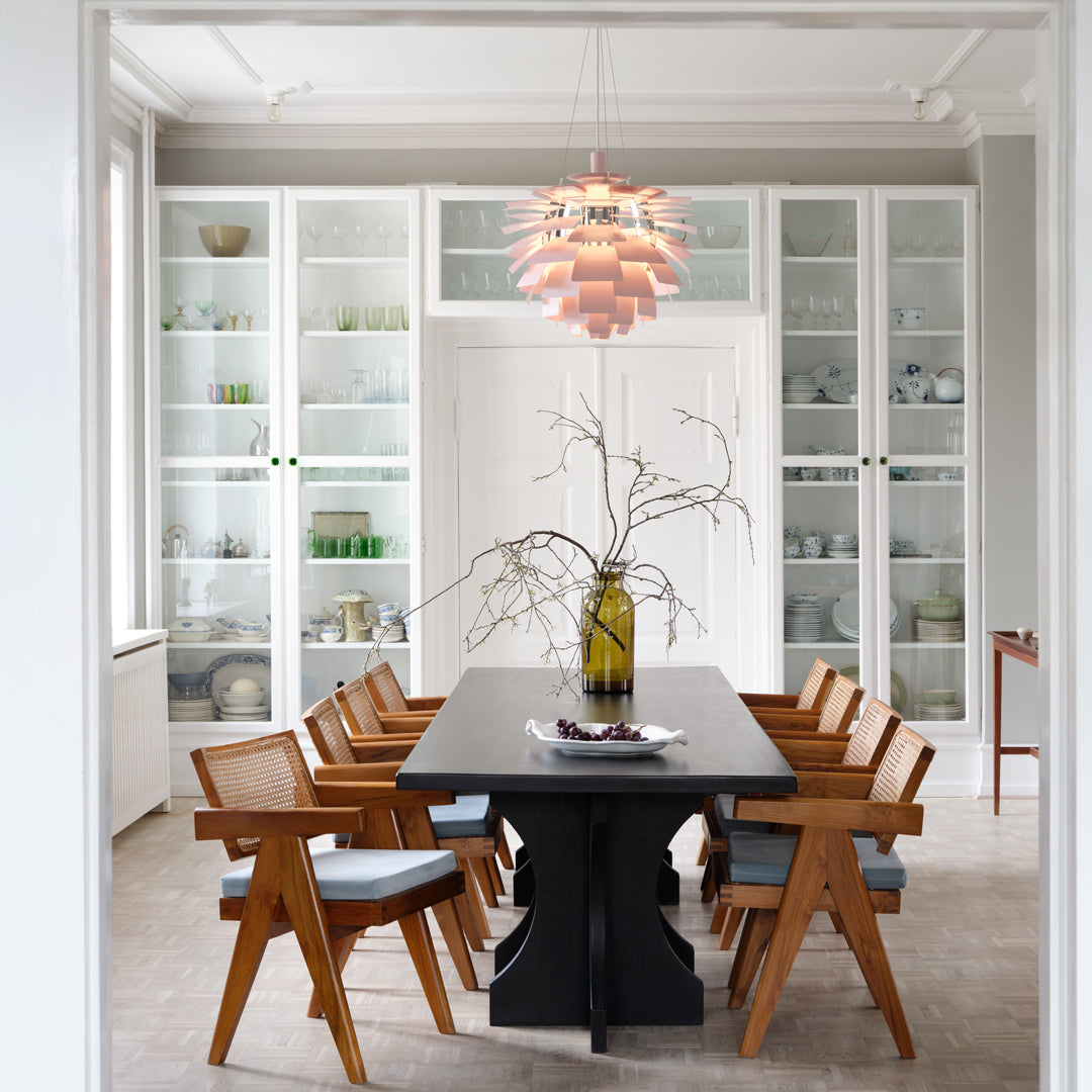 Modern dining room featuring a black table, natural wood chairs, and soft pastel lighting. Bright, minimalist decor.