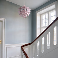 "Soft pink lamp with layered design in a light blue and white interior setting."