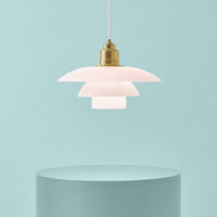 Pink layered pendant lamp with a brass finish against a soft blue background. Modern design with elegant curves.