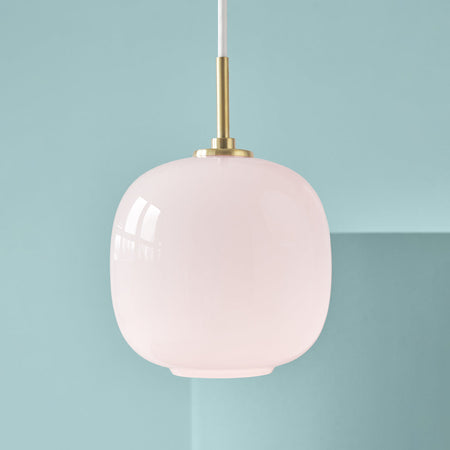 Soft pink glass pendant light with a smooth finish and a sleek gold accent against a light blue background.