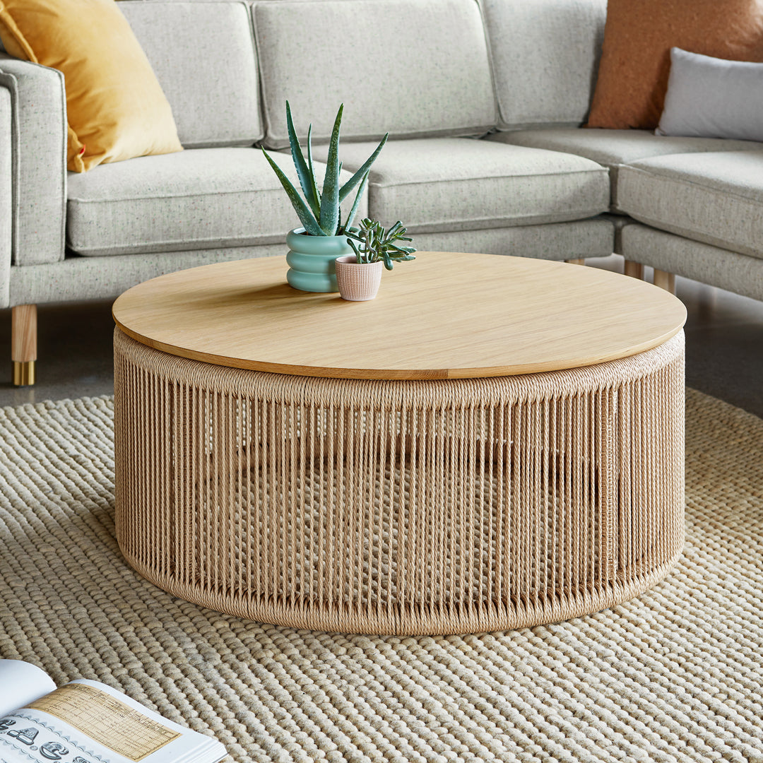 Round wooden coffee table with natural bamboo weave and light oak top, set on a textured beige rug.
