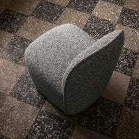Gray textured chair on a checkered brown and black floor. Modern design with soft curves and subtle patterns.