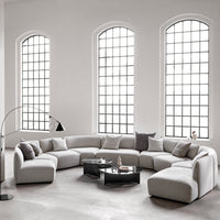 Modern gray sectional sofa with minimalist design, featuring soft fabric and sleek lines in a bright, airy space.