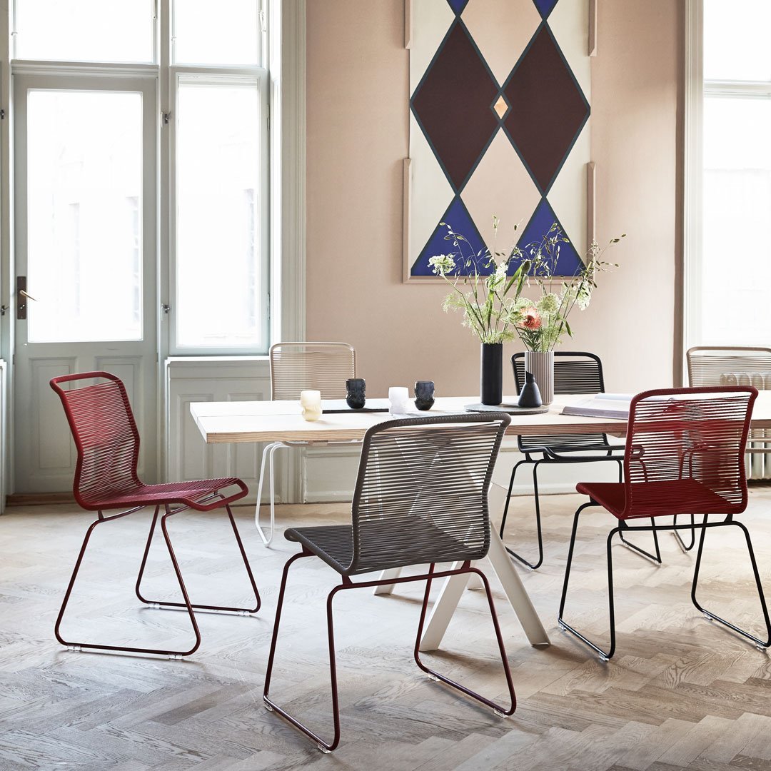 Red and gray mesh chairs with geometric wall art in blue and white, set in a light, airy room.