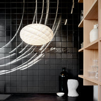 "Black tiled wall with soft white light, featuring sleek lines and subtle shadows for a modern aesthetic."