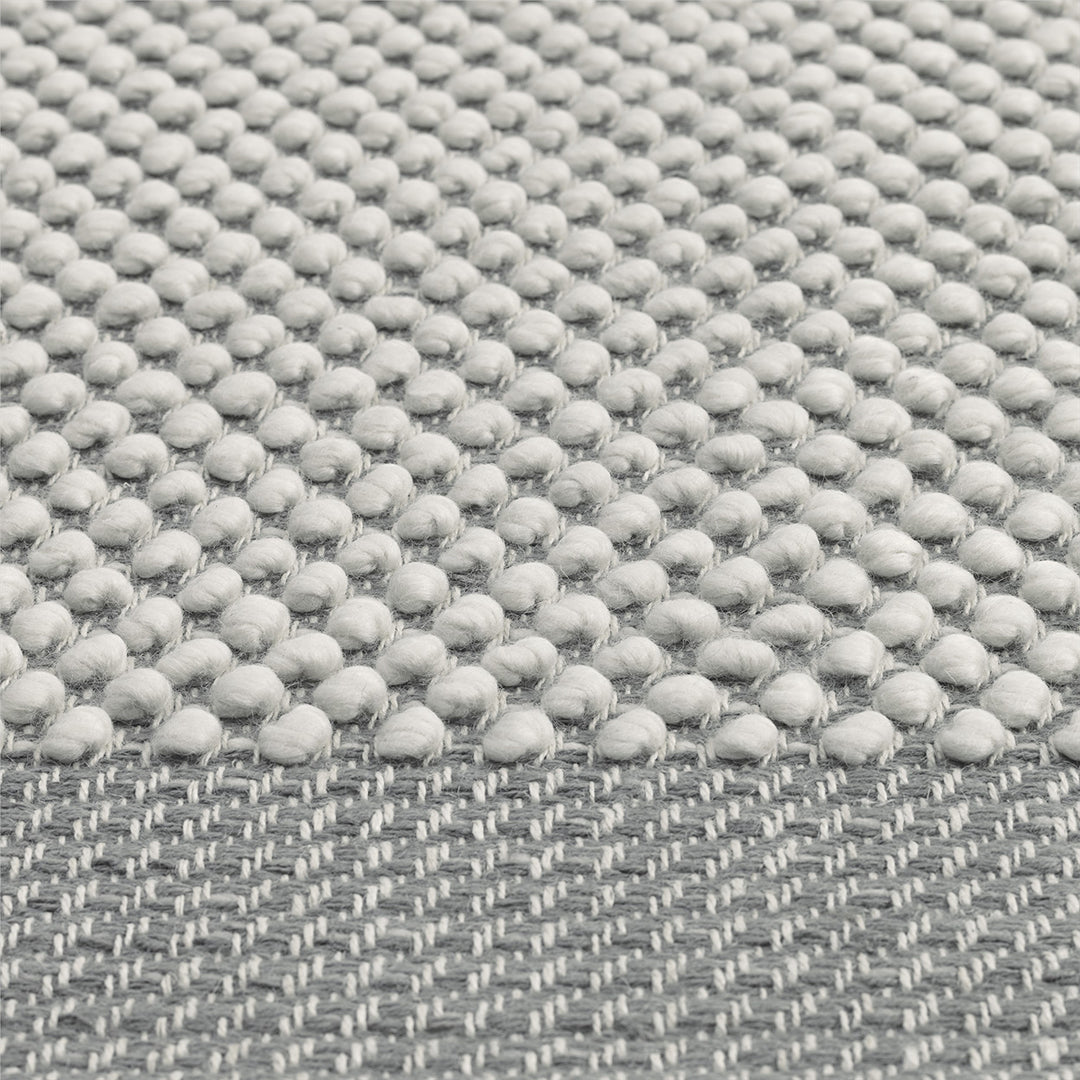 Light gray textured fabric featuring a dotted pattern with a smooth woven edge. Perfect for modern decor.