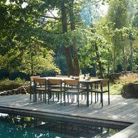 Outdoor dining set featuring a natural wood finish with a sleek black frame, set against a lush green backdrop.