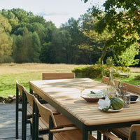 Light wood table with natural finish, complementing beige chair cushions and green outdoor scenery. 