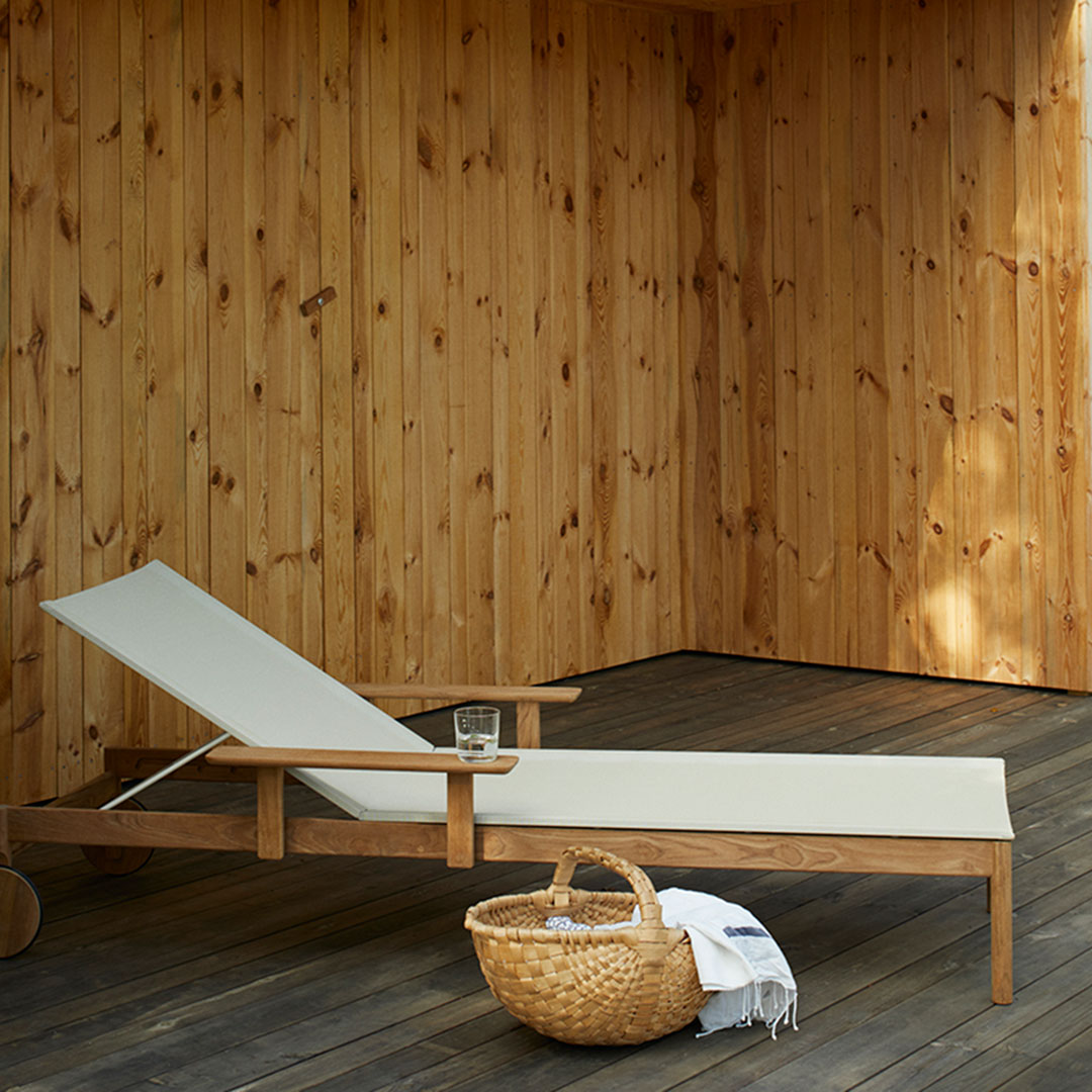 "Neutral cream chaise lounge on wooden deck against a warm, natural wood backdrop."