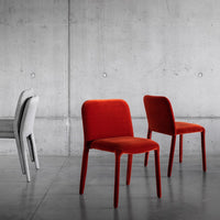 "Set of modern chairs in vibrant red and soft gray velvet against a sleek concrete backdrop."