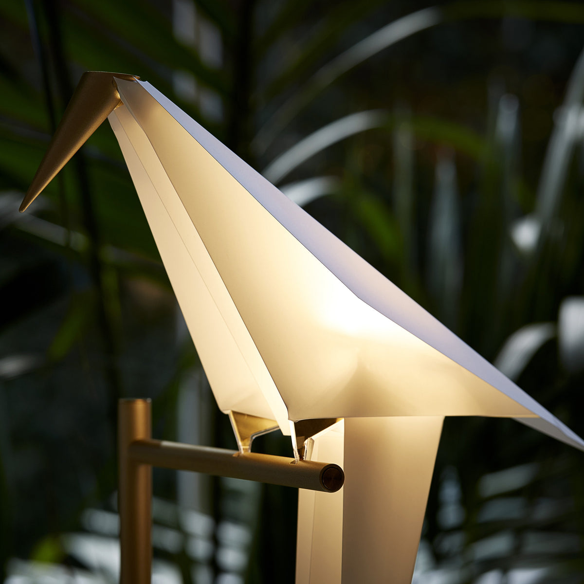 Elegant white paper lamp shaped like a bird, featuring soft light and minimalistic design against a green backdrop.