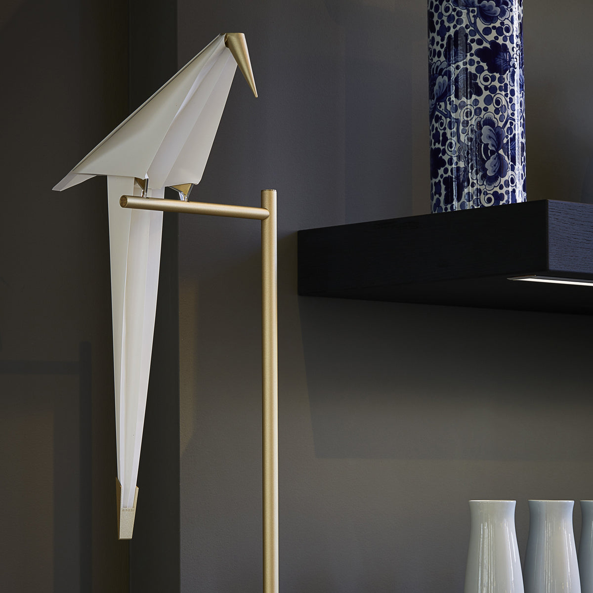 Elegant white origami bird decor with gold accents, complemented by deep blue patterned vase and white ceramic vases.