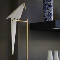 Elegant white origami bird decor with gold accents, complemented by deep blue patterned vase and white ceramic vases.