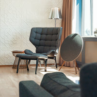 Modern gray upholstered chair with textured pattern, paired with a round accent table and soft, neutral-toned decor.