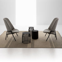 Gray chairs on a beige striped rug with black accent tables, featuring modern geometric patterns and neutral tones.