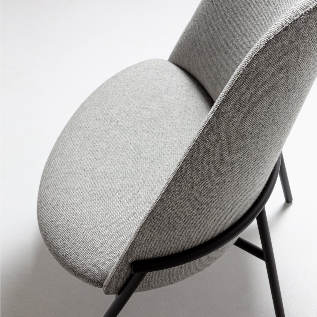 Gray upholstered chair with a smooth, oval seat and contrasting black frame, showcasing a minimalist design aesthetic.