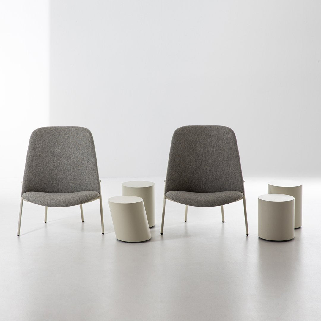 Two modern gray upholstered chairs with sleek metal legs, paired with minimalist white cylindrical stools.
