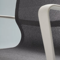 Modern black mesh chair with a sleek white armrest, showcasing a textured pattern and minimalist design.
