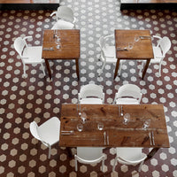 Wooden tables and white chairs on a patterned brown and white geometric floor. Perfect for stylish dining spaces.