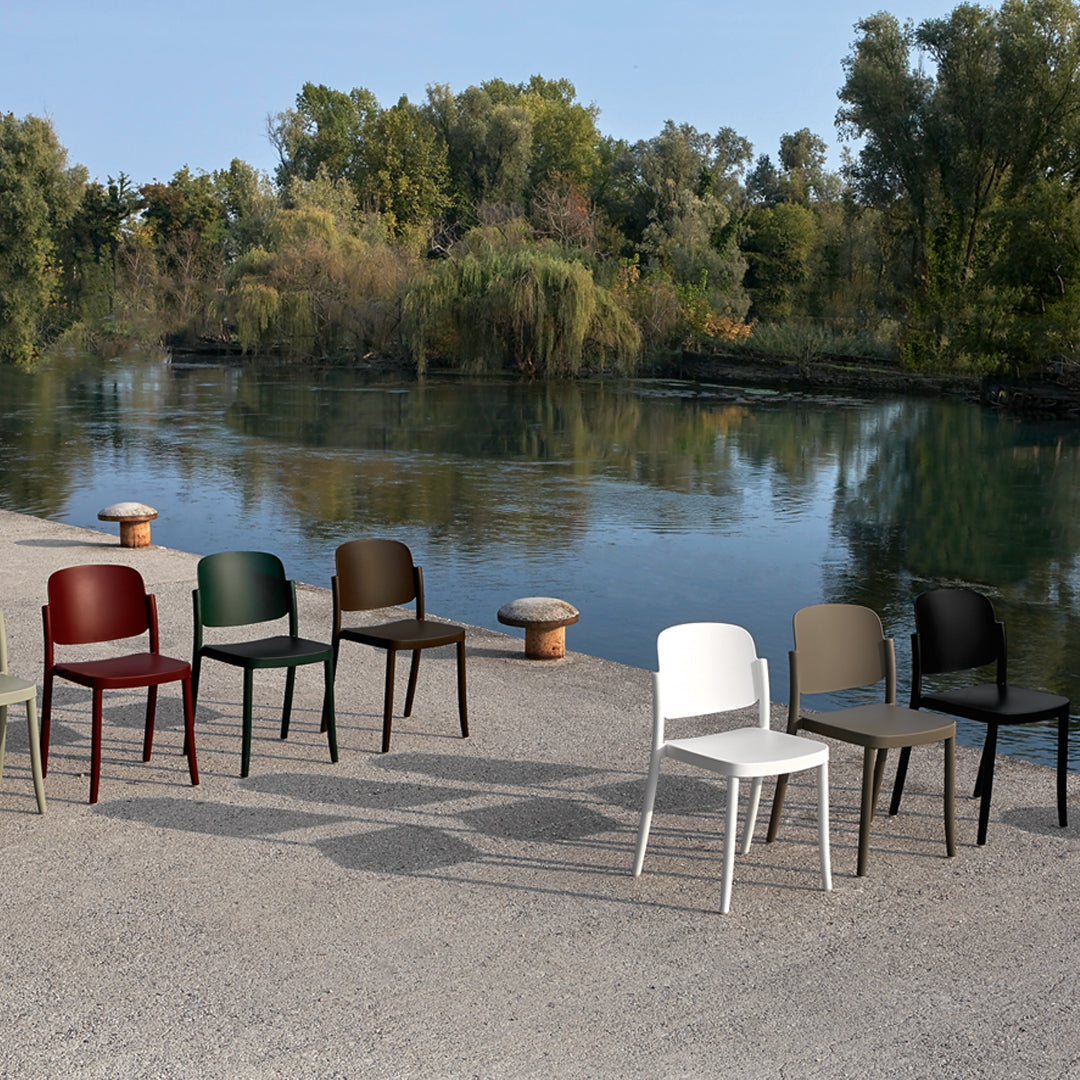 Colorful outdoor chairs in white, black, green, brown, and beige against a serene lakeside backdrop.