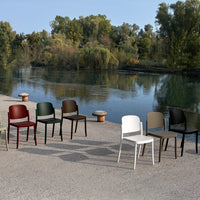 Colorful outdoor chairs in white, black, green, brown, and beige against a serene lakeside backdrop.