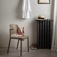 Stylish taupe chair with a soft pink throw, contrasted by dark gray radiator and light wall for a modern look.