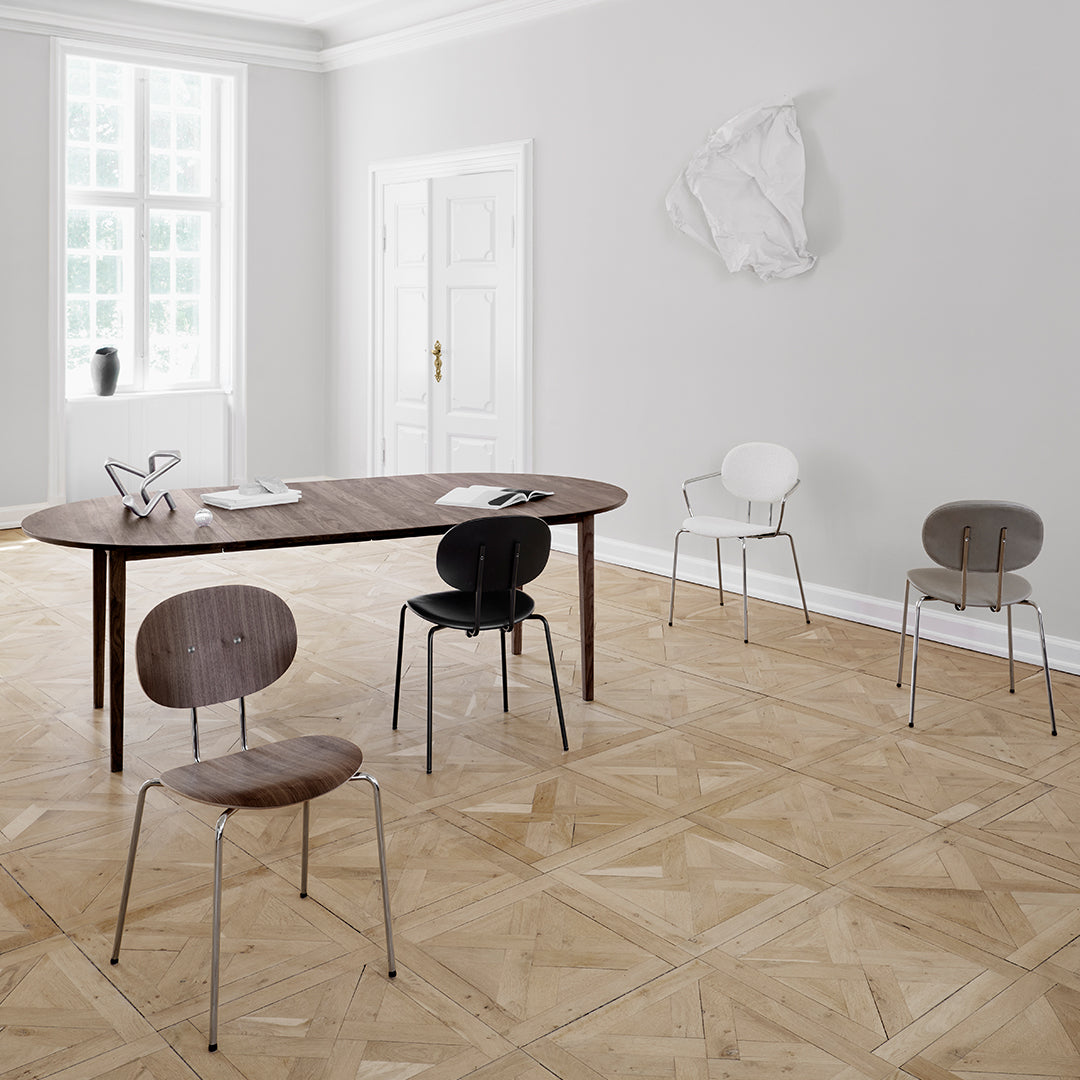 Elegant wooden dining table surrounded by black, white, and natural wood chairs on a textured parquet floor.