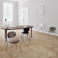 Elegant wooden table with gray and black chairs on a light wood patterned floor in a bright, modern room.