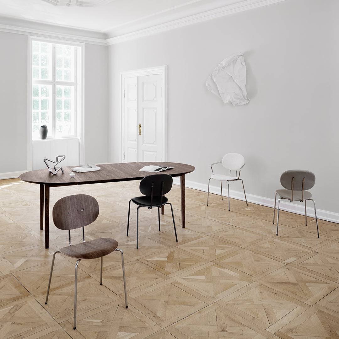 Stylish wooden table with neutral-toned chairs in black, white, and brown, set against a pale gray room.