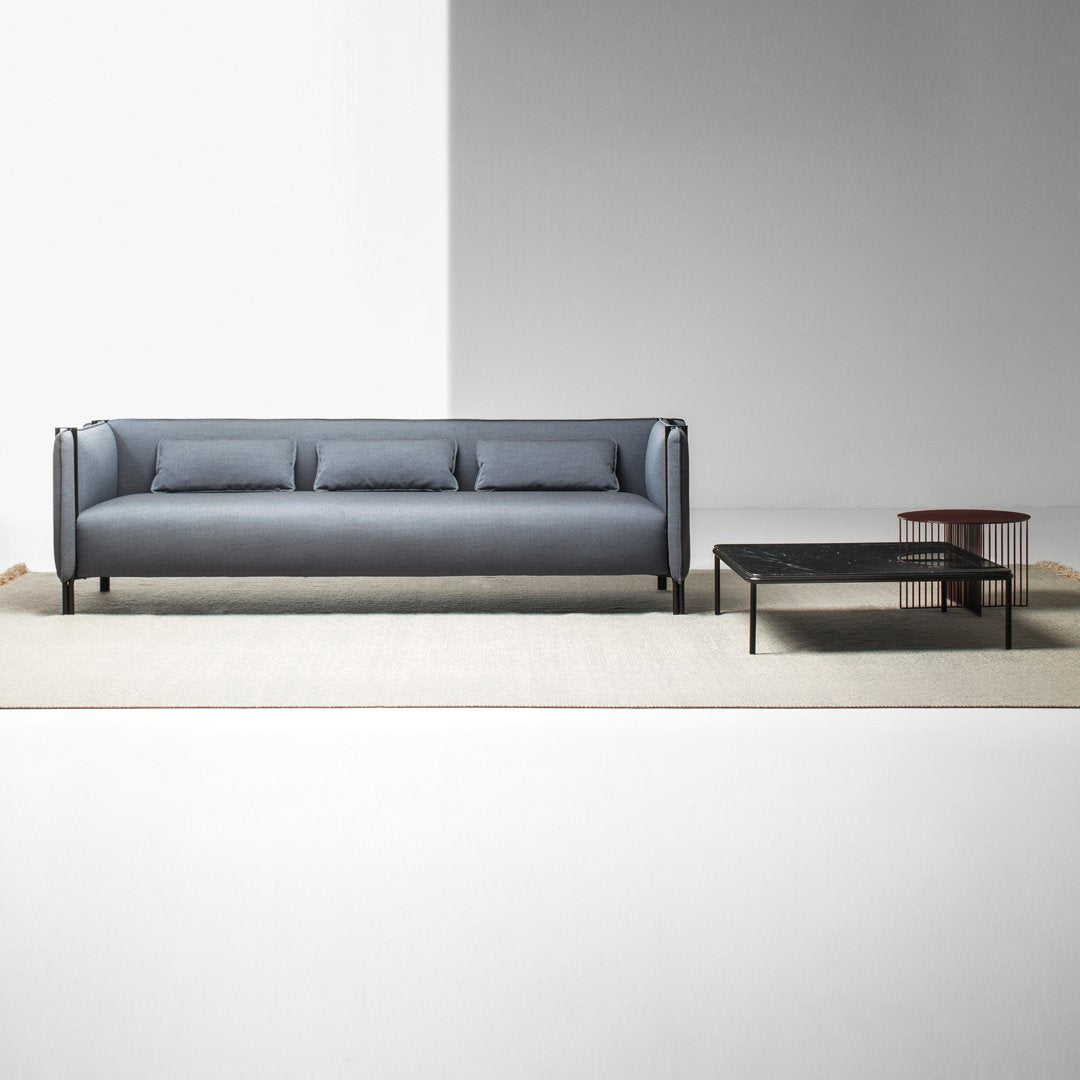 Modern gray sofa with three cushions, paired with a sleek black coffee table on a soft beige rug.