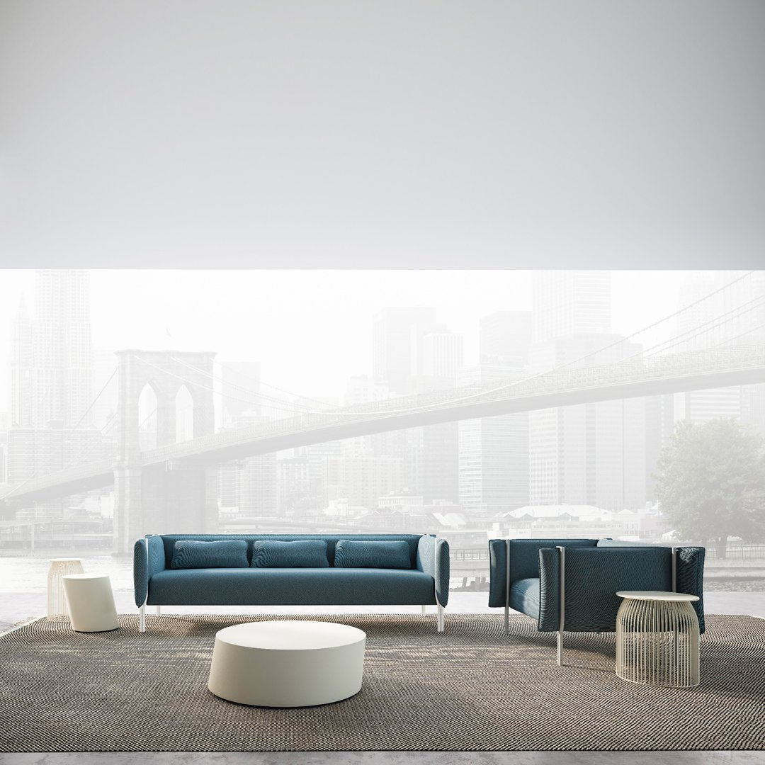 Teal fabric sofa and armchair with white accents, set on a textured brown rug against a soft gray background.