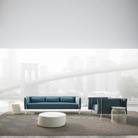 Teal fabric sofa and armchair with white accents, set on a textured brown rug against a soft gray background.