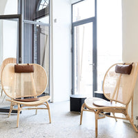 Natural rattan chairs with a circular design and light brown cushions, set against a bright, airy room backdrop.