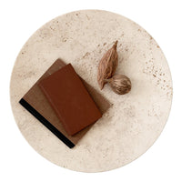 Brown and tan notebooks on a textured cream plate, surrounded by natural brown nuts. Minimalist design and earthy colors.