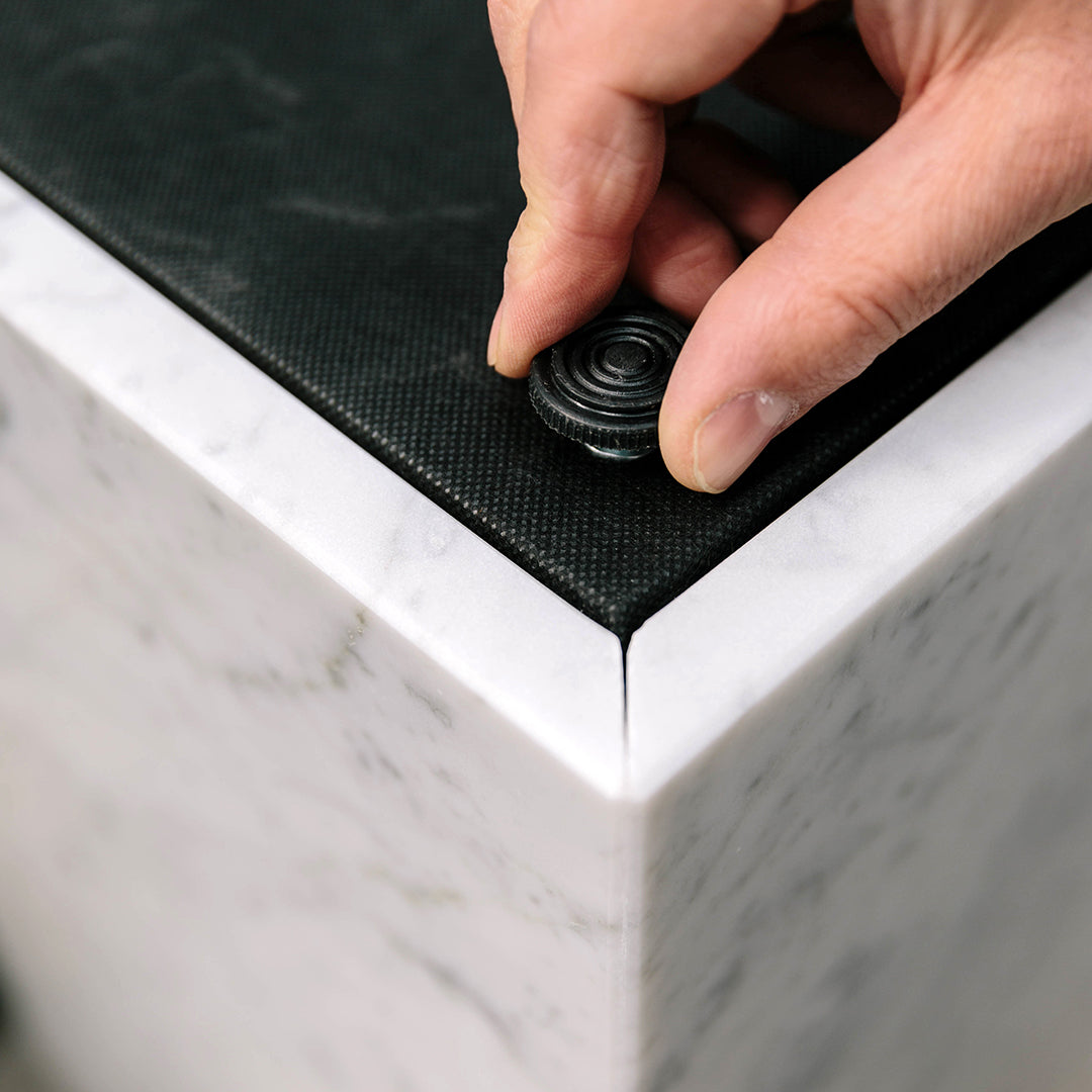 Black textured top on a sleek white marble base, showcasing a modern design with subtle patterns.