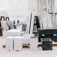 "Variety of white and black marble blocks with unique patterns, displayed in a bright workshop setting."
