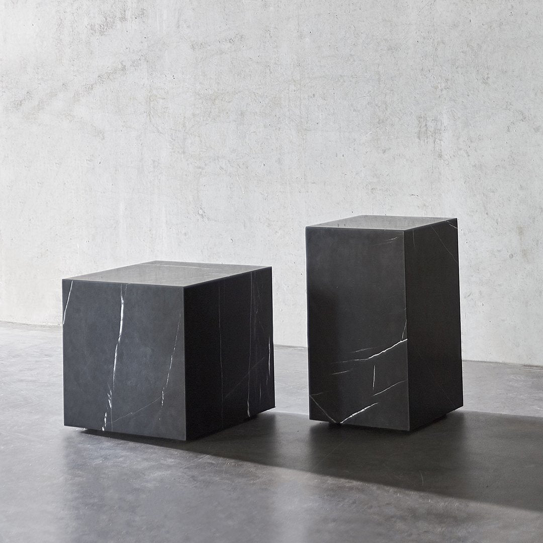 Two modern black marble side tables showcasing sleek geometric shapes and subtle white veining patterns.