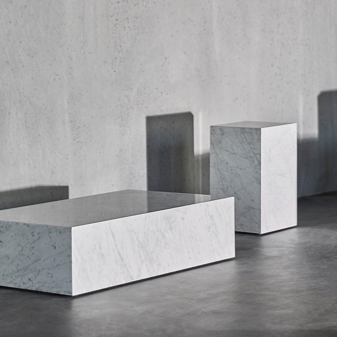 White marble blocks with sleek surfaces, casting subtle shadows against a gray concrete backdrop.