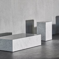 White marble blocks with sleek surfaces, casting subtle shadows against a gray concrete backdrop.