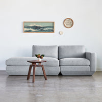 Light gray sectional sofa with a smooth, minimalist design, complemented by a wooden side table.