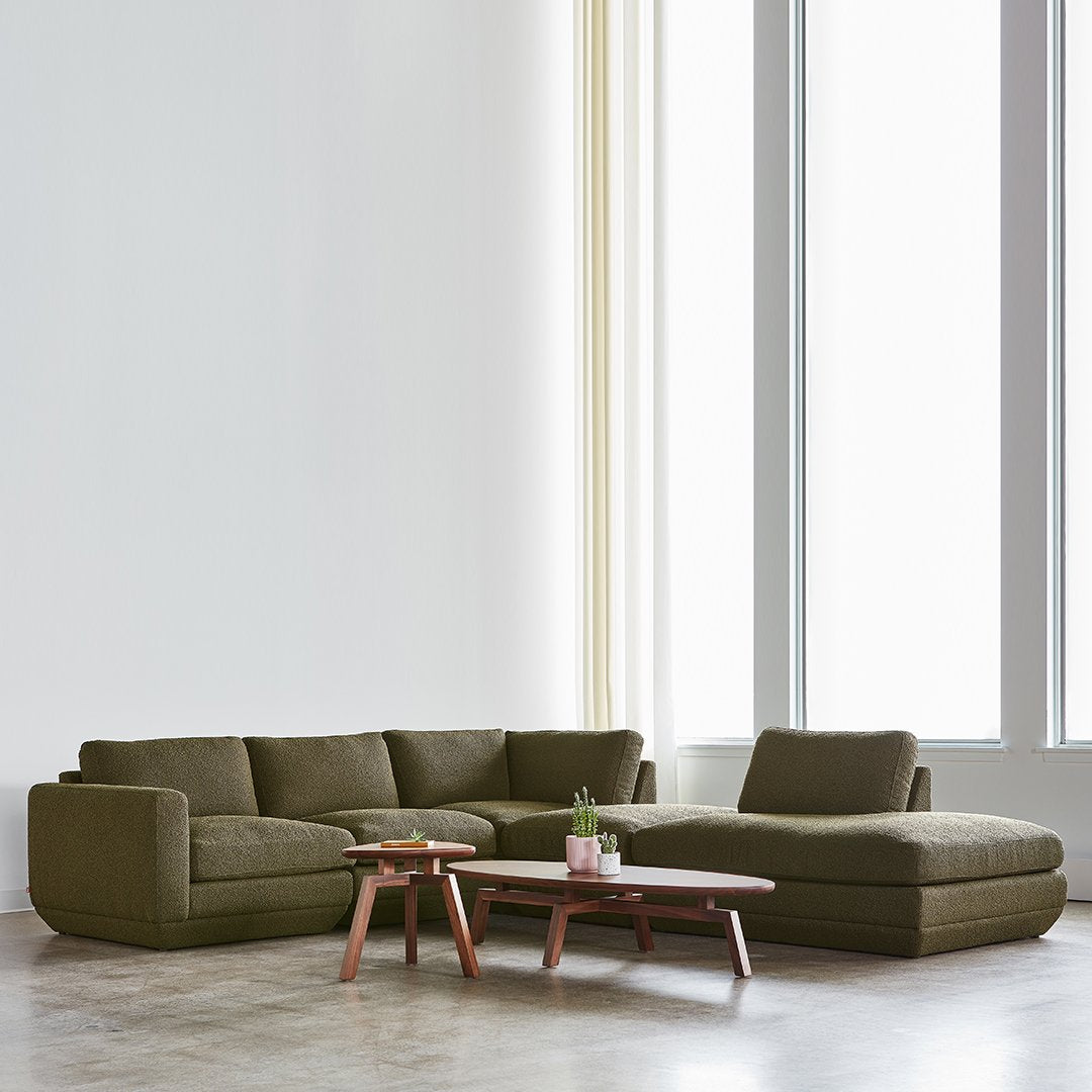 Olive green sectional sofa with smooth fabric and minimalist design, paired with a simple wooden coffee table.