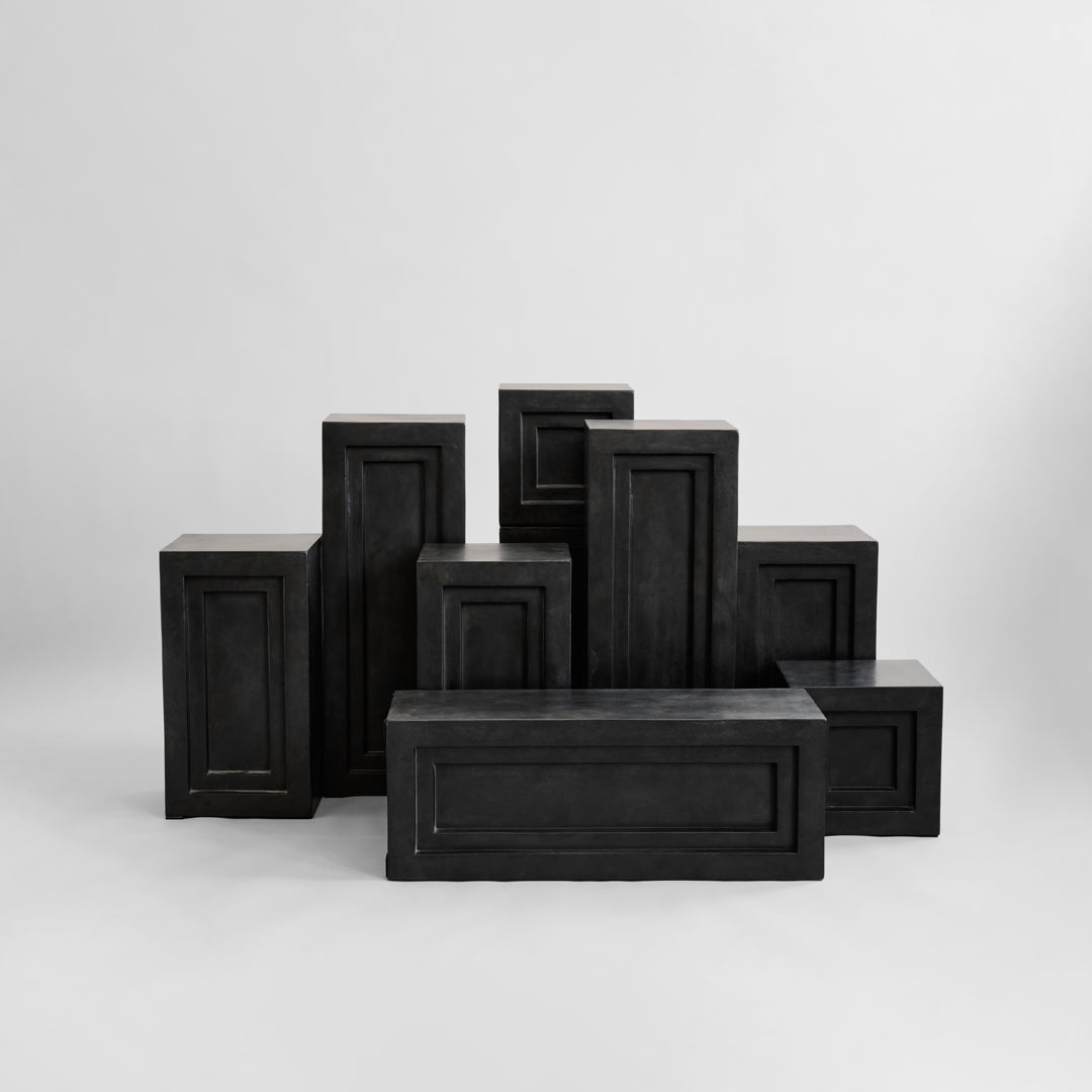 Black decorative blocks with textured surfaces and layered geometric patterns, creating a modern aesthetic.