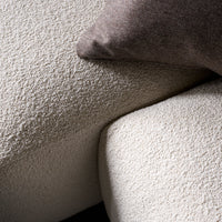 Textured light beige fabric with a cream cushion and a dark gray throw pillow, showcasing a modern aesthetic.