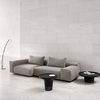 Gray sofa with clean lines and subtle textures paired with black round table, set against a minimalistic backdrop.