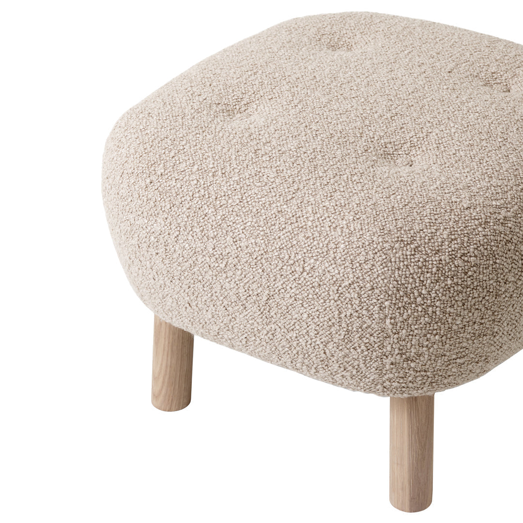 Beige tufted pouf with soft, textured fabric and natural wood legs, perfect for adding warmth to any space.