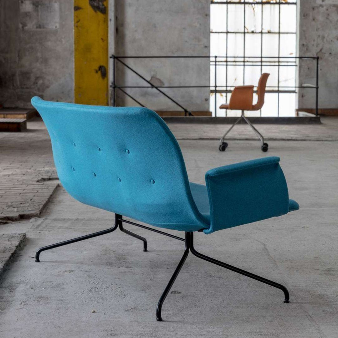 Turquoise upholstered chair with button details on black metal legs, set in an industrial-style space.