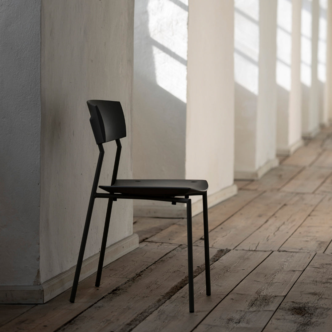 Sleek black chair with a minimalist design, featuring clean lines against a light wooden floor.
